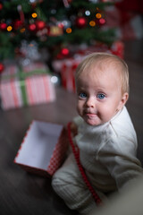 A baby toddler near a Christmas tree