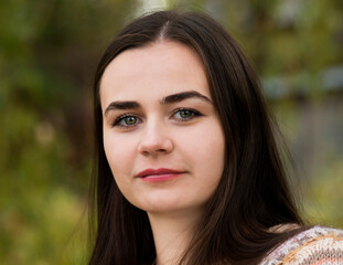 Naklejka premium Portrait of a dark-haired green-eyed woman on the background of nature 