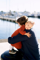 Father and daughter are hugging on a boat pier while having a family day