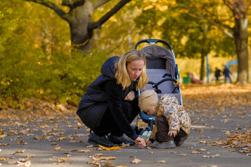 Happy family: mom and daughter draw on the asphalt with chalk in the autumn park. Fallen...