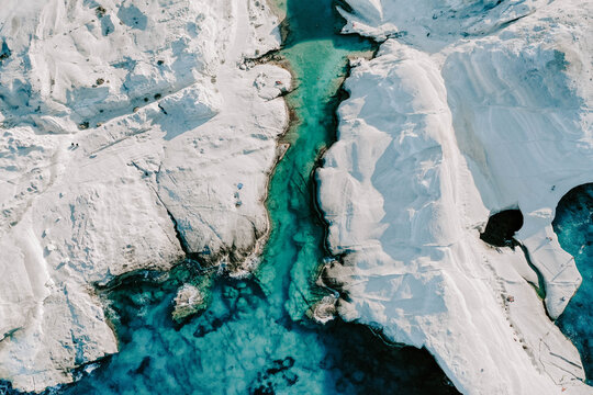 Aerial drone photographs of Sarakiniko Beach moonscapes in Milos Island, Greece surrounded by crystal clear turquoise waters and waves of the Aegan Sea