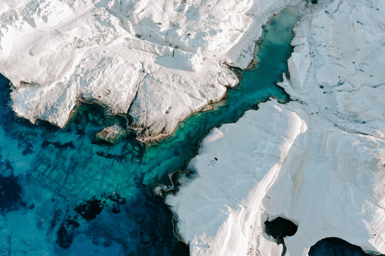 Aerial drone photographs of Sarakiniko Beach moonscapes in Milos Island, Greece surrounded by crystal clear turquoise waters and waves of the Aegan Sea