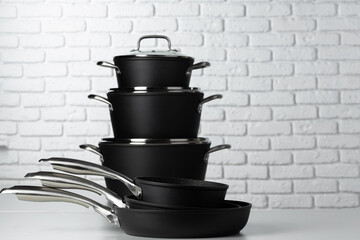 Set of cookware on table against white brick wall