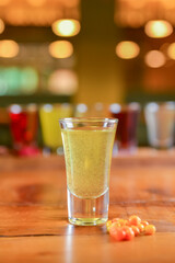 Tincture alcoholic in small shot glasses. Natural fruit alcohol drinks, shots served on a wooden table.