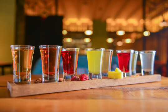 Tincture alcoholic in small shot glasses. Natural fruit alcohol drinks, shots served on a wooden table.