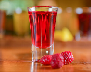 Tincture alcoholic in small shot glasses. Natural fruit alcohol drinks, shots served on a wooden table.