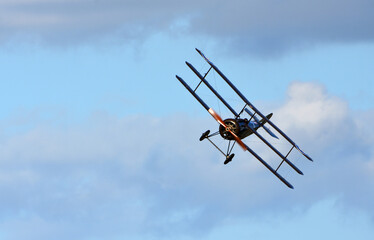 Vintage  Sopwith Triplane  in flight blue sky  and clouds view from front