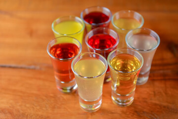 Tincture alcoholic in small shot glasses. Natural fruit alcohol drinks, shots served on a wooden table.