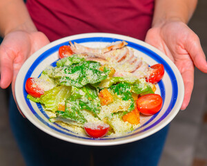 Bowl of Caesar Salad. Waiter in restaurant holds a plate of Italian caesar salad. Traditional Italian cuisine.