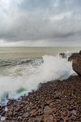 Powerful waves hit the rough stone coast line creating huge splashes of water. Low dark storm clouds, West of Ireland. Nobody.