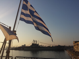 An impressive huge Greek flag, waves on a flag pole. Αt the stern of a frigate, named Kountouriotis (F-462). One of Hellenic Navy warships. Anniversary of "NO DAY".