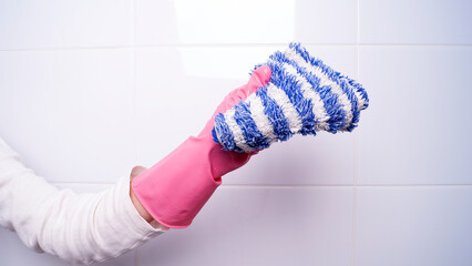 female hand in a rubber glove holding a rag for cleaning surfaces