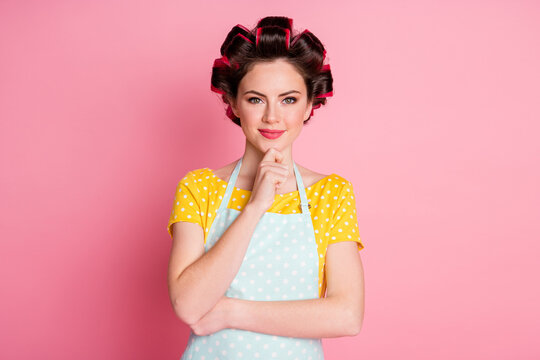 Portrait of minded girl maid touch hands chin plan ponder solution wear hair rollers isolated on pink color background