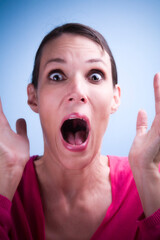 Dark haired woman looking at camera and screaming with a surprised or scared facial expression.
