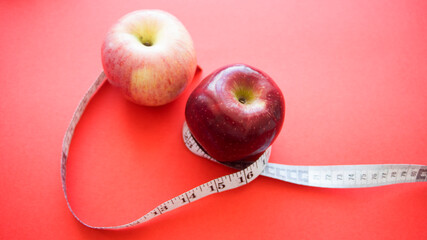 apples with measuring tape on red background