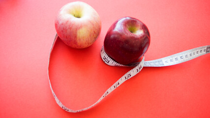 apples with measuring tape on red background