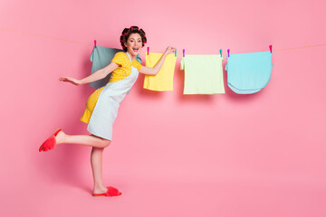 Full length body size view of her she nice cheerful housekeeper hanging on line soft wet fresh laundry textile isolated pink pastel color background