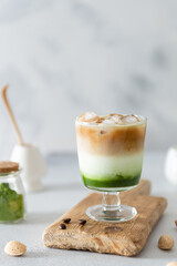 Matcha green tea espresso, matcha green tea with milk, ice and coffee on a wooden board. Layered matcha drink. Fresh summer drink. Side view, copy space. Menu, recipe
