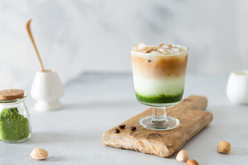 Matcha green tea espresso, matcha green tea with milk, ice and coffee on a wooden board. Layered matcha drink. Fresh summer drink. Side view, copy space. Menu, recipe