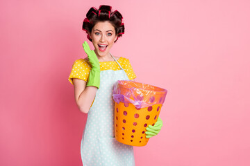 Portrait of nice attractive cheerful cheery glad brown-haired maid holding in hands trash basket isolated over pink pastel color background