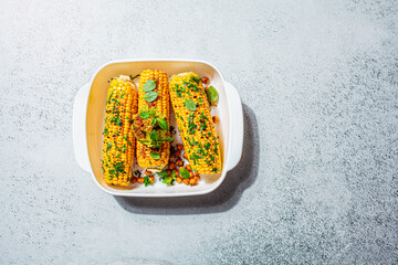 Grilled whole corn with herbs in a white dish, top view. Vegetarian food concept.