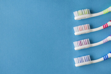 Four clean toothbrushes on a blue background. Copy space