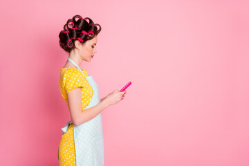 Profile side view portrait of pretty focused housemaid blogger using gadget blogging post smm browsing isolated on pink color background