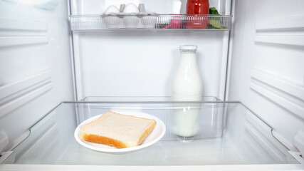 One lonely slice of bread inside an empty fridge