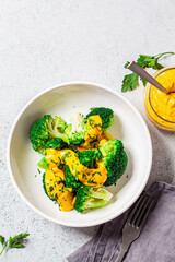 Broccoli with cheese sauce in white bowl, top view. Healthy food concept.