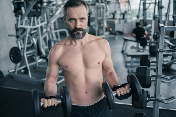 Training in gym, Handsome man with a mustache, do muscle building exercises using dumbbells, focusing on lifting and sit-ups in a fitness sport
