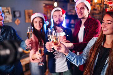 Happy group of young friends touching the glasses with each other. Friends celebrating winter holidays in luxury nightclub together. Relax, clinking wineglass, surprise.