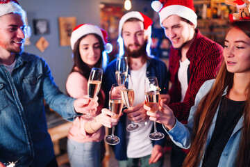 Happy group of young friends touching the glasses with each other. Friends celebrating winter holidays in luxury nightclub together. Relax, clinking wineglass, surprise.