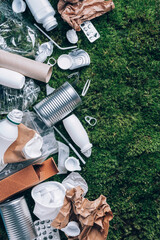 Food plastic packaging, trash on green moss background after picnic in forest. Top view. Copy...