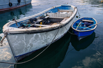 Fototapeta na wymiar Kavarna, Bulgaria - September 2016: Large and small blue fishing boats lie next to each other in the harbor in the evening sun