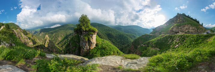 Fototapeta na wymiar Wonderful panoramic view of majestic sunny landscape with wooded mountain cliff and colorful sky over the fairytale mountain valley. Caucasus, Russia