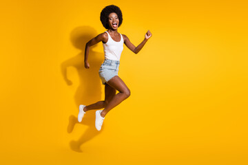 Full length body size view of active energetic cheerful wavy-haired girl jumping running fast isolated over bright yellow color background