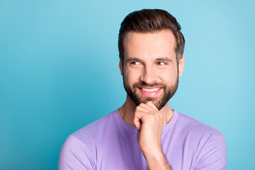 Photo of young cheerful young man happy positive smile hand touch chin think look empty space isolated over blue color background