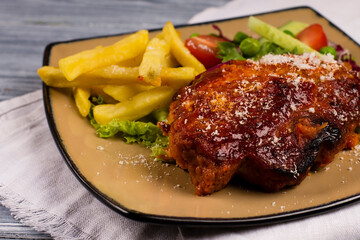 Italian parmesan chicken with fries and tomatoes, on a plate