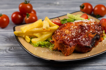 Italian parmesan chicken with fries and tomatoes, on a plate