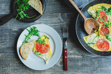 tasty italian style vegetarian breakfast - fried eggs frittata ot omelete with mozarella cheese, arugula and tomatoes