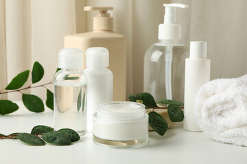 Spa cosmetic products and leaves on white table