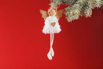 Handmade christmas angel toy on a Christmas tree on a red background.