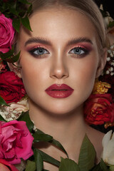 Portrait of a beautiful young girl with stylish make-up decorated with beautiful live roses