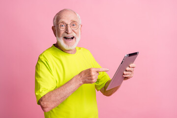 Portrait of funky pensioner pointing on tablet wear spectacles green color t-shirt isolated on...