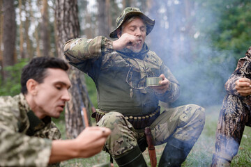 Men Enjoy Lunch Outdoor Campfire Picnic in Woods.