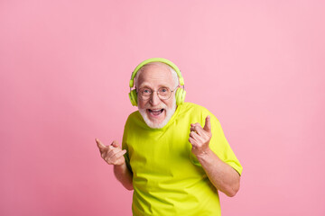 Photo of crazy old man listen music dance wear headphones spectacles lime color clothes isolated on pink background
