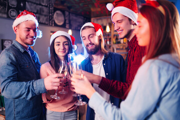 Group of happy friends celebrating  new year's party.  A crowd of young  people with sparklers, gifts and clinking glass. Party, holidays,  nightlife, holidays. Christmas.