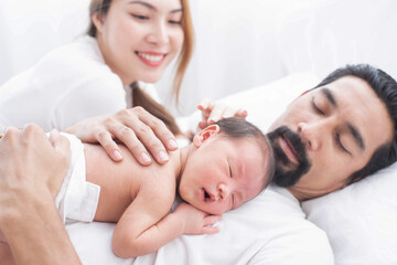 smiling mother and father holding their newborn baby at home..portrait of happy family at home, young parents holding on hands little sweet newborn baby, love and happiness concept.