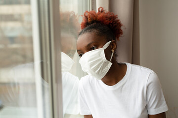 young african woman in medical mask near the window