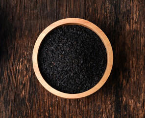 Sesame on wooden table. Top view. Black sesame in a bowl isolated on wooden background.